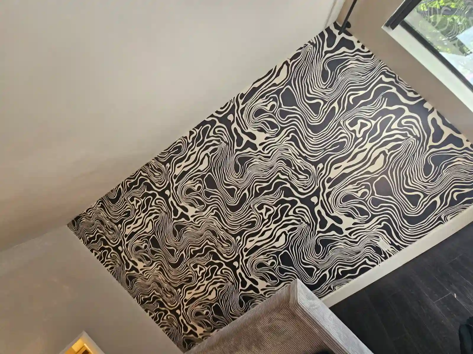 Stair landing with a bold black-and-white abstract contour-pattern wallpaper accent wall.